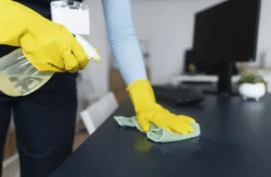 immagine ravvicinata di una donna che pulisce una scrivania di un ufficio con un panno