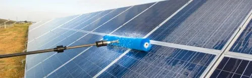 Una persona che pulisce un pannello fotovoltaico, con una spugna e un detergente, per mantenere l'efficienza dell'impianto fotovoltaico.